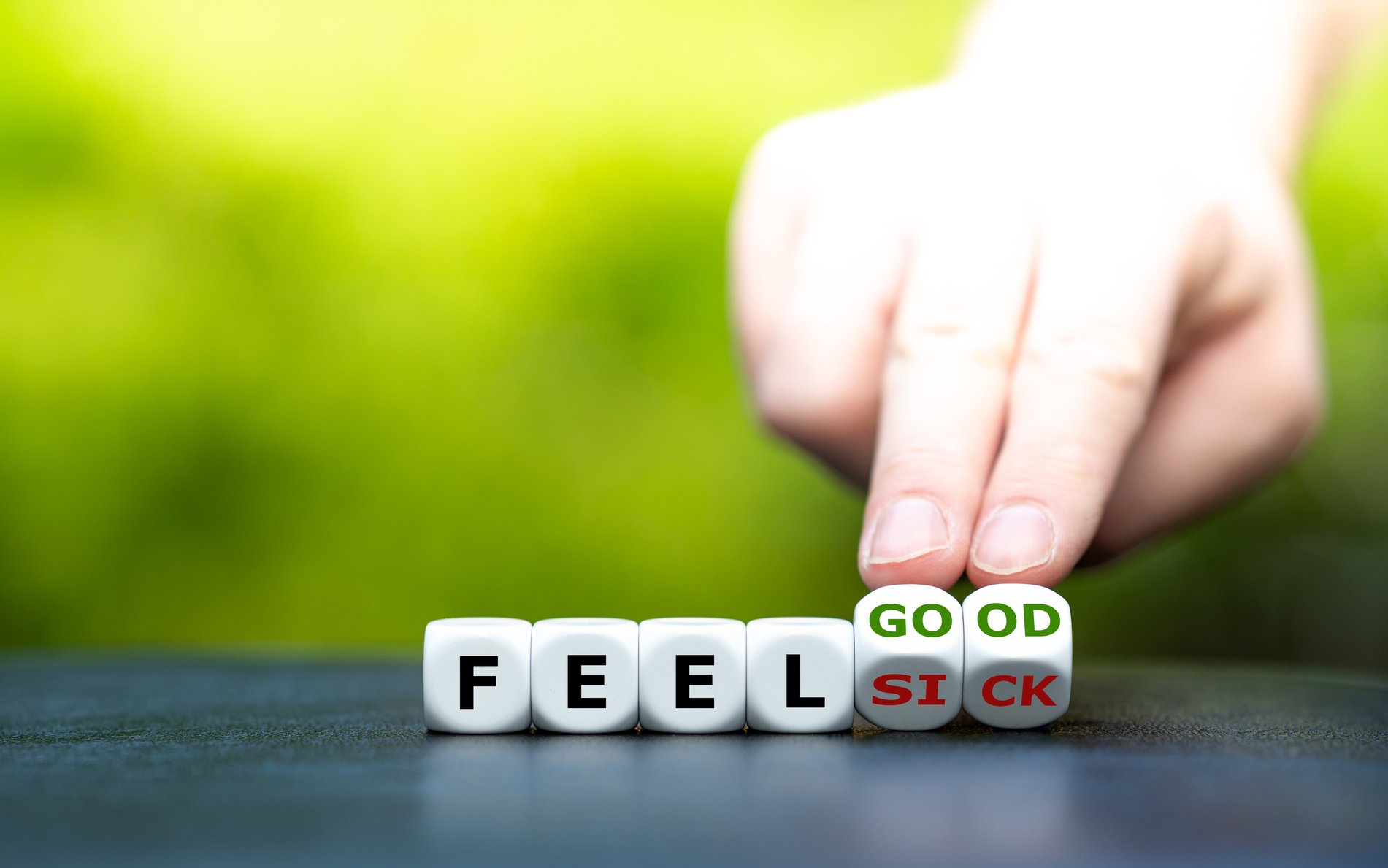 Hand turns dice and changes the expression "feel sick" to "feel good".